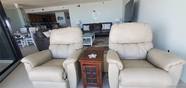 a living room with a flat screen tv on dresser and a table with wooden floor