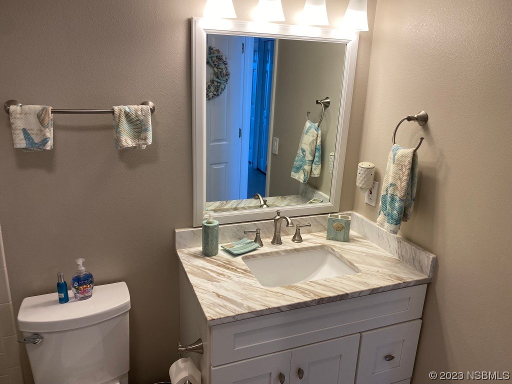 6727 Turtlemound Road, Unit 416 New Smyrna Beach, FL 32169 - Photo 39 of 67 a bathroom with a granite countertop sink a toilet and a mirror