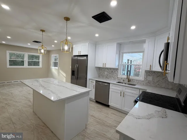 a kitchen with stainless steel appliances kitchen island granite countertop a sink a stove a refrigerator and island with wooden floor