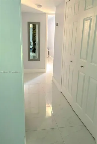a view of a hallway with wooden floor and a bathroom