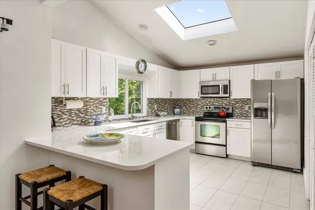 a kitchen with a refrigerator a stove a sink cabinets and a dining table