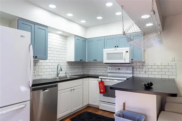a kitchen with a sink a stove a refrigerator and black cabinets