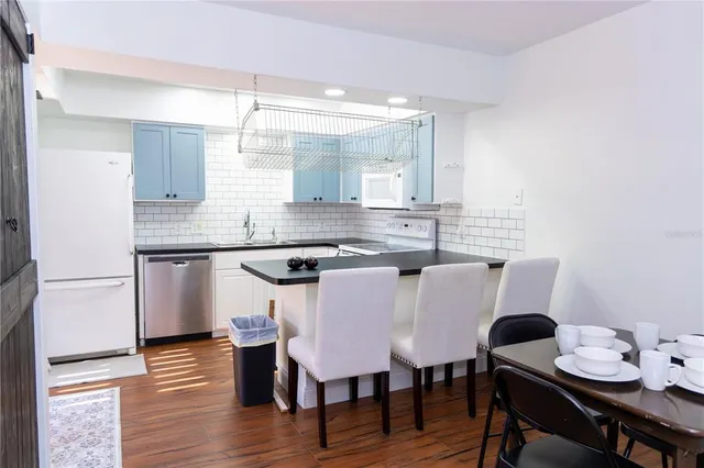 a kitchen with stainless steel appliances granite countertop a dining table chairs and a refrigerator