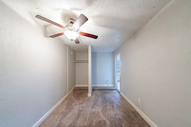 an empty room with windows and fan