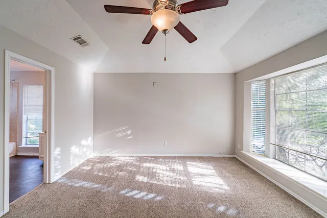 an empty room with ceiling fan and window