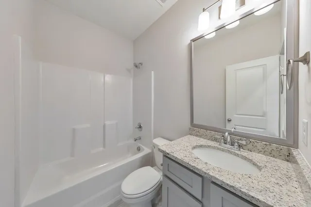a bathroom with a granite countertop sink a toilet and shower