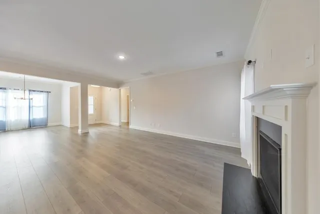 a view of an empty room with wooden floor and fireplace
