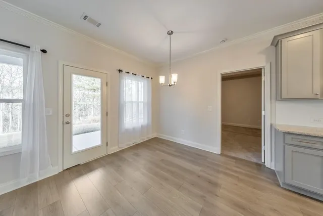 a view of an empty room with window and wooden floor