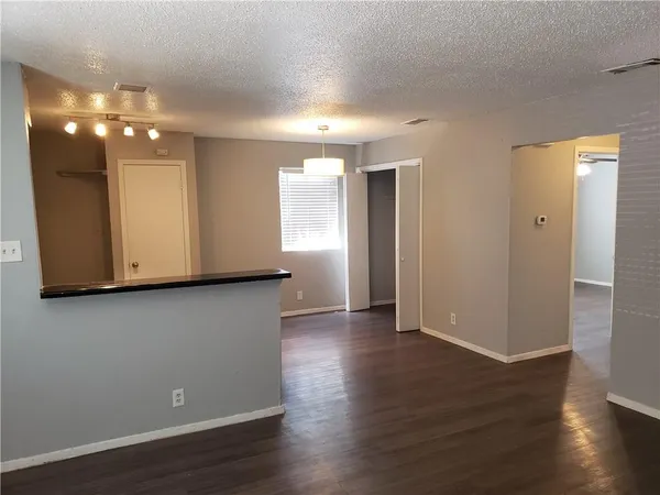 a view of an empty room with wooden floor and cabinets