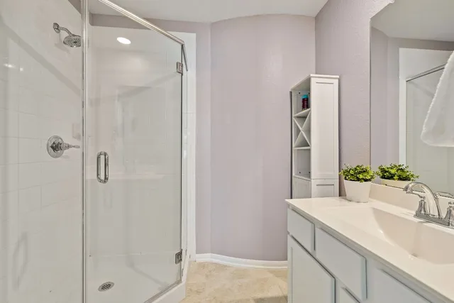 a bathroom with a granite countertop sink a mirror and shower