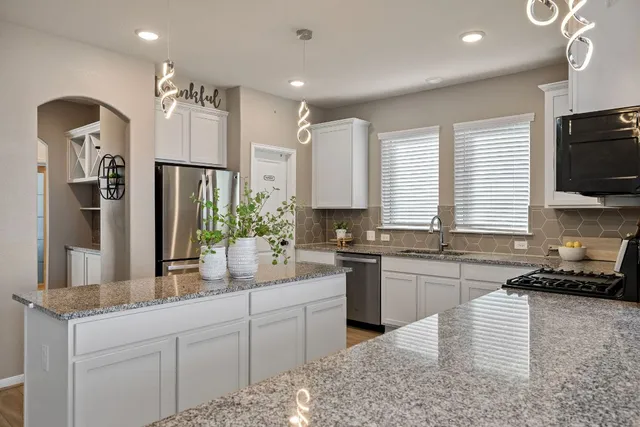 a kitchen with kitchen island granite countertop a sink a counter space appliances and cabinets