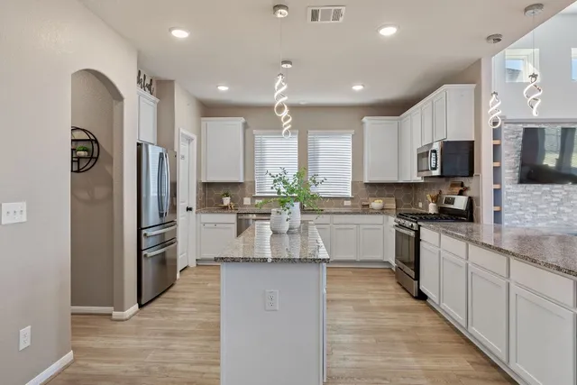 a kitchen with stainless steel appliances granite countertop a refrigerator sink stove microwave and cabinets