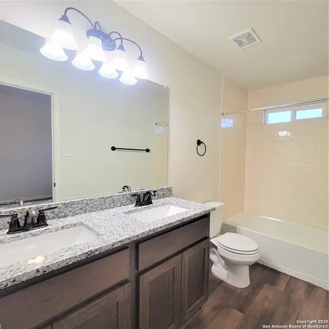 a bathroom with a granite countertop sink a toilet and a large mirror