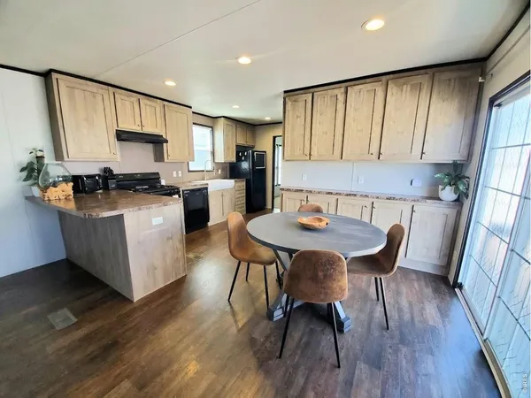 a kitchen with stainless steel appliances granite countertop a stove top oven a sink dishwasher a dining table and chairs with wooden floor