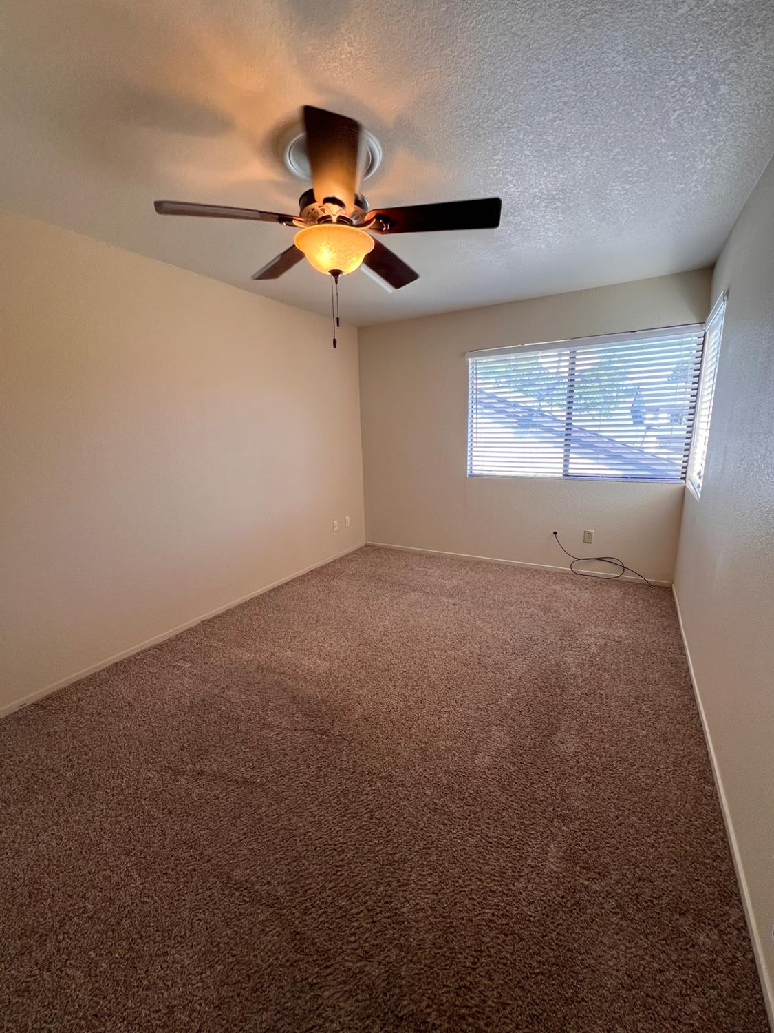 1417 West Swain Road Stockton, CA 95207 - Photo 15 of 18 en empty room with windows and ceiling fan