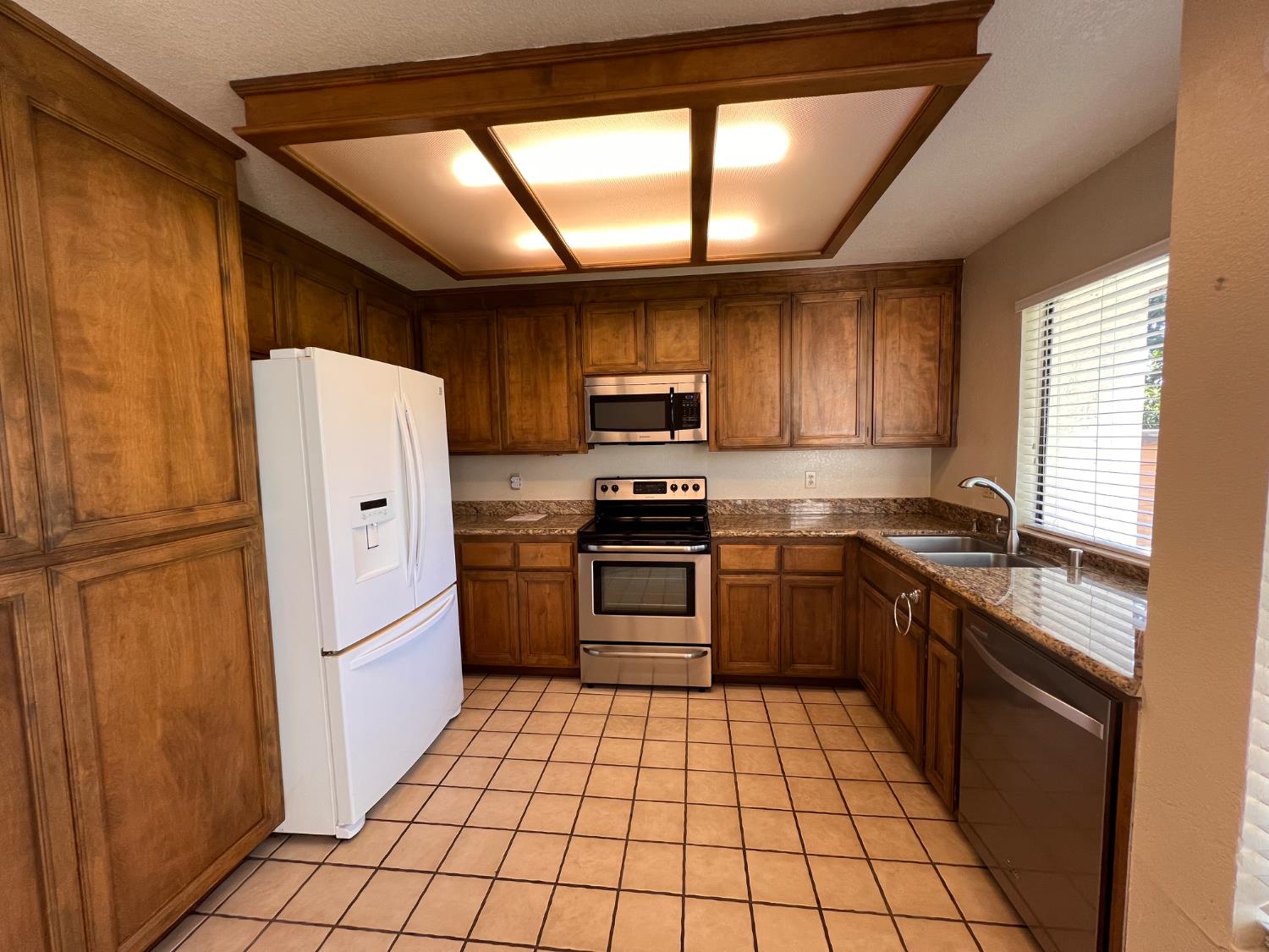 1417 West Swain Road Stockton, CA 95207 - Photo 10 of 18 a kitchen with granite countertop a refrigerator and a stove top oven