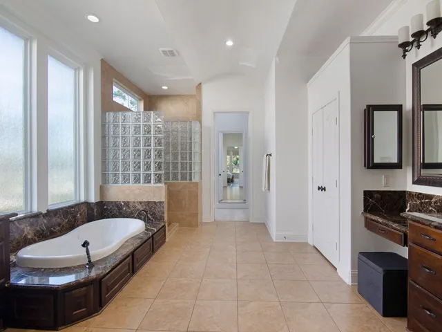 a spacious bathroom with a granite countertop tub shower and mirror