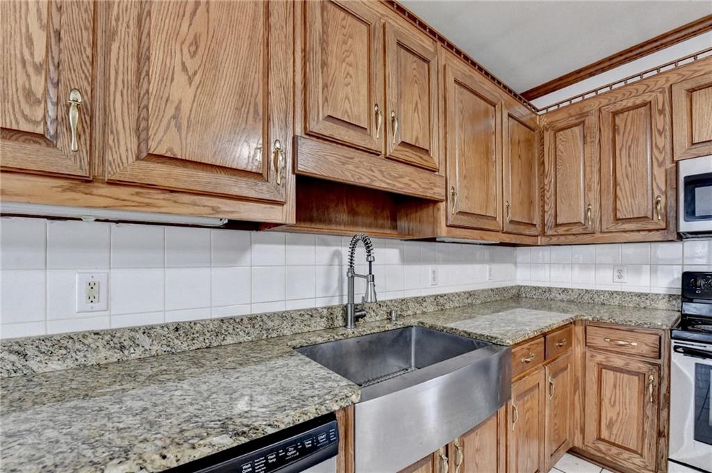 1622 New Hope Road Lawrenceville, GA 30045 - Photo 28 of 110 a kitchen with granite countertop a sink stainless steel appliances wooden cabinets and a counter top space