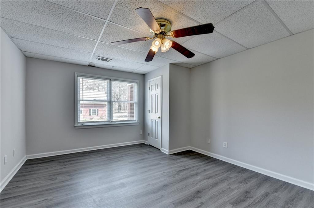 1622 New Hope Road Lawrenceville, GA 30045 - Photo 72 of 110 an empty room with wooden floor chandelier fan and windows