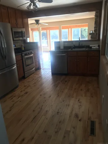a view of a kitchen with wooden floor and stainless steel appliances