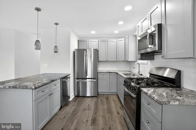 a kitchen with stainless steel appliances granite countertop a refrigerator a stove a sink and a microwave