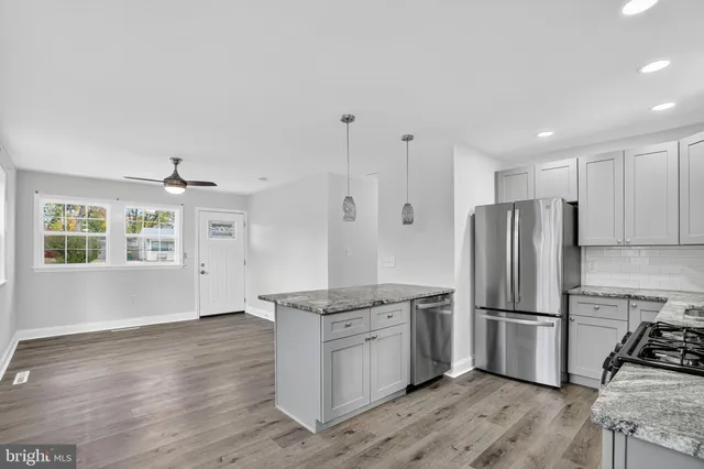 a kitchen with granite countertop stainless steel appliances a refrigerator cabinets and wooden floor