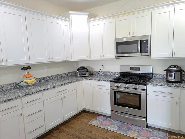 a kitchen with granite countertop white cabinets and stainless steel appliances