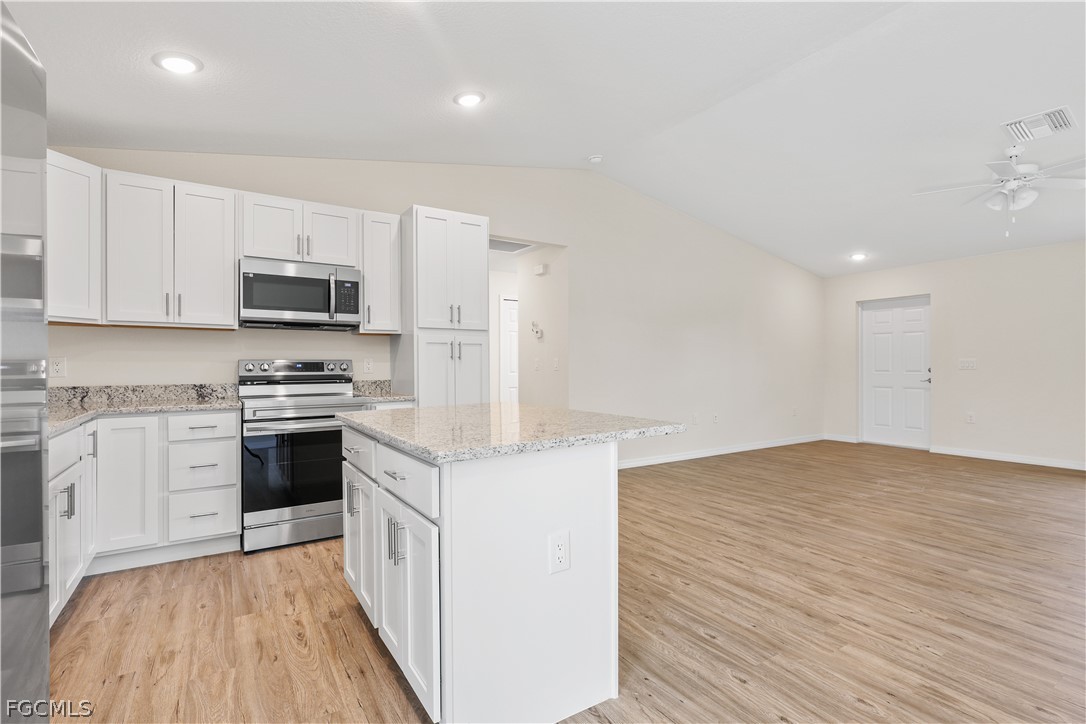 4524 Springview Circle LaBelle, FL 33935 - Photo 11 of 25 a kitchen with granite countertop a stove top oven a sink dishwasher and a refrigerator with wooden floor