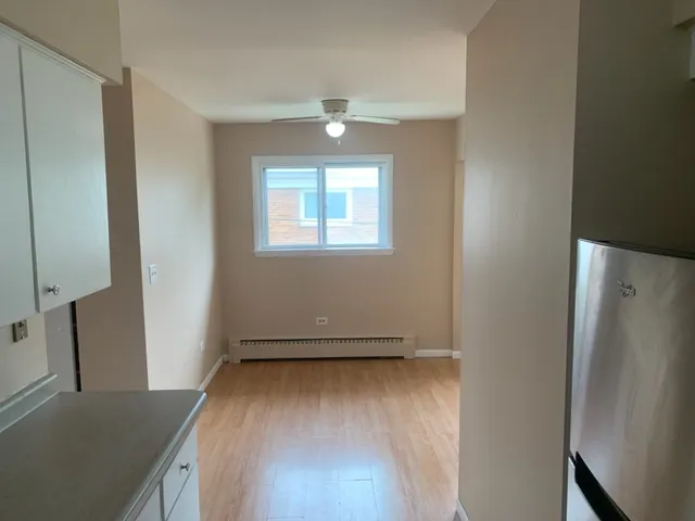 an empty room with wooden floor cabinet and windows