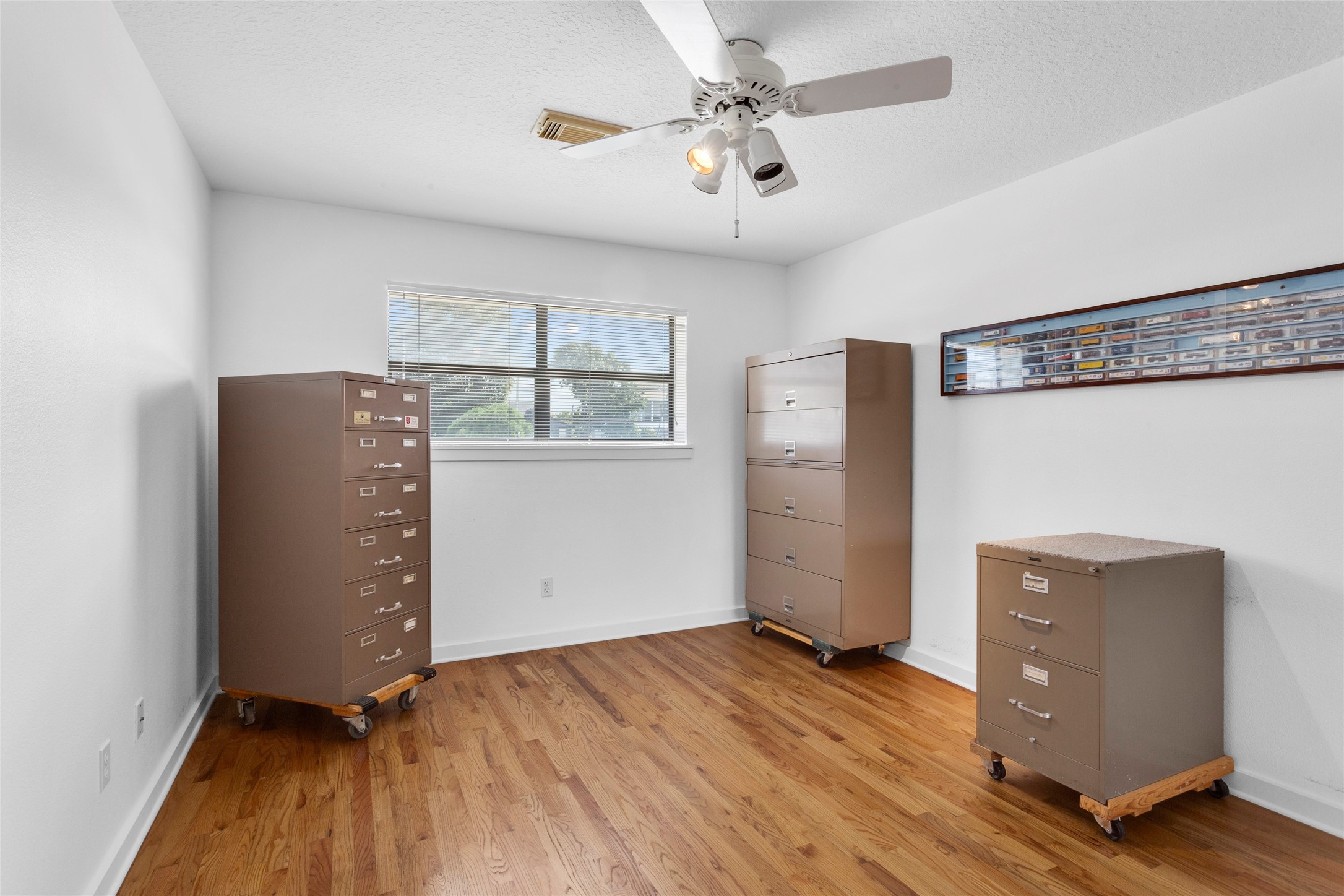 67 Harbor Lane Kemah, TX 77565 - Photo 21 of 47 This bedroom features a clean, minimalist design with hardwood flooring and a ceiling fan. It's well-lit by a large window.