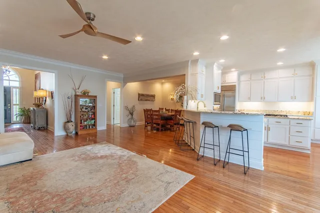 a open kitchen with stainless steel appliances granite countertop a refrigerator dining table and chairs a oven with wooden floors