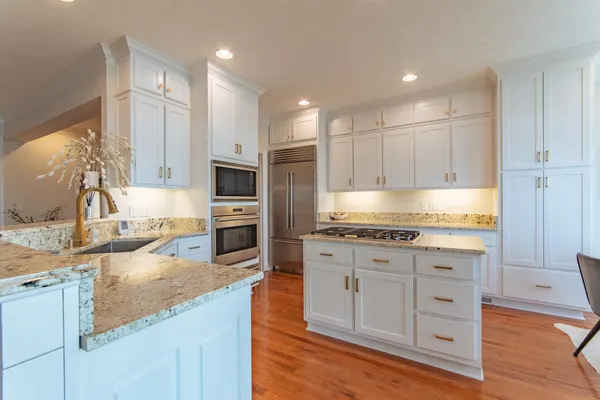 a large kitchen with granite countertop a large counter top stainless steel appliances and cabinets