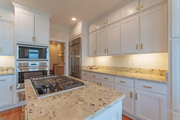 a kitchen with kitchen island granite countertop a sink stove and cabinets