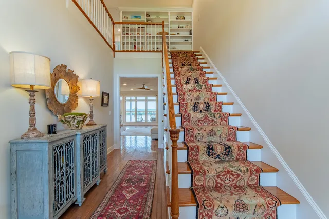 a view of a hallway to a livingroom with wooden floor and staircase
