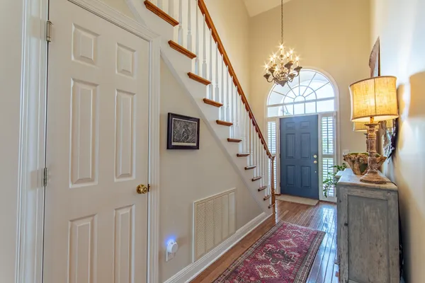 a view of a livingroom with furniture stairs wooden floor and chandelier