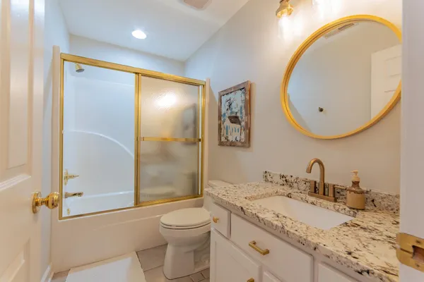 a bathroom with a granite countertop sink mirror vanity and toilet