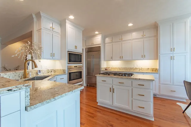 a large kitchen with granite countertop a large counter top stainless steel appliances and cabinets