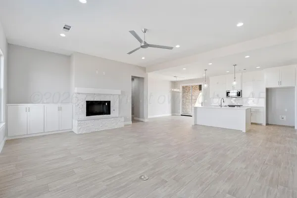 a view of an empty room with kitchen and a window