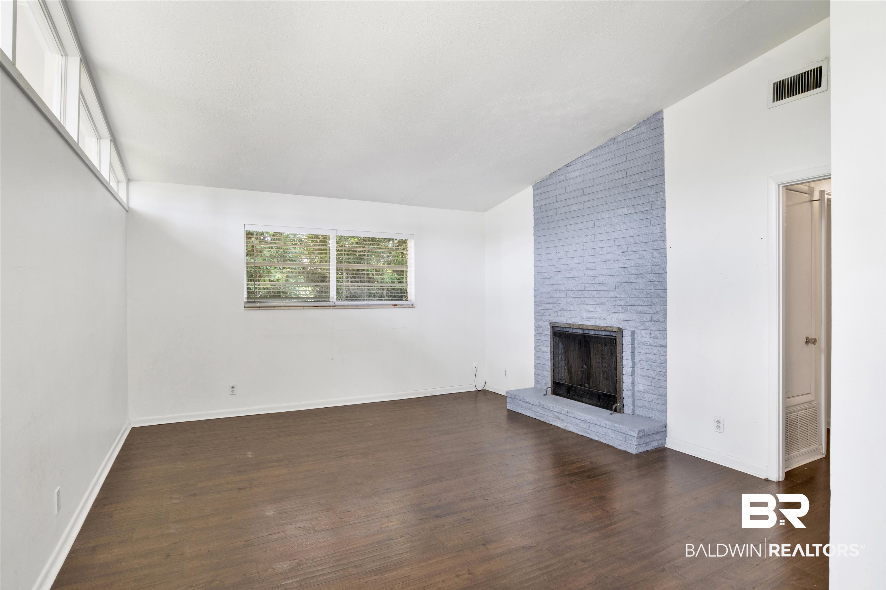 2 Lee Circle Daphne, AL 36527 - Photo 7 of 21 Unfurnished living room featuring a fireplace, vaulted ceiling, dark hardwood / wood-style floors, and brick wall