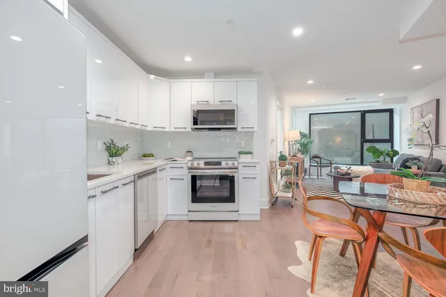 a kitchen with stainless steel appliances a stove a sink a refrigerator and a white cabinets