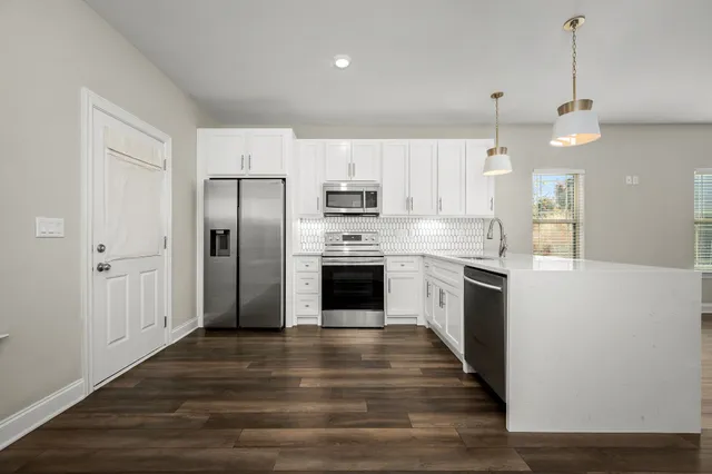 a large kitchen with cabinets wooden floor and stainless steel appliances