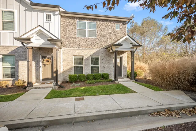 a view of a white house next to a yard with potted plants
