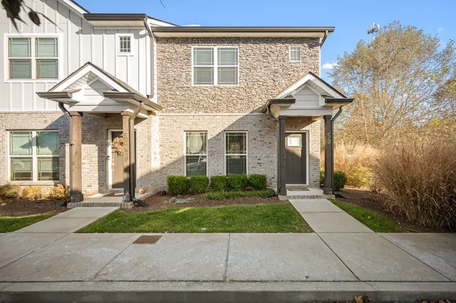 a front view of a house with a yard and potted plants