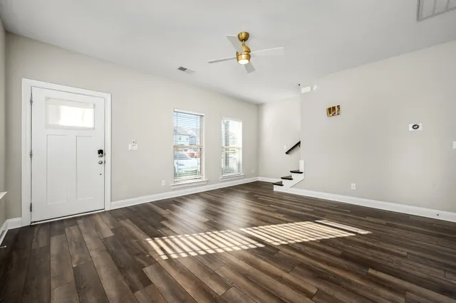 a view of an empty room with wooden floor and a window