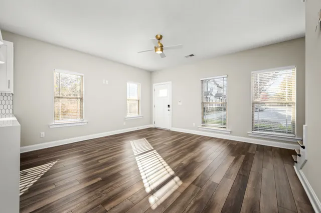 a living room with kitchen island dining table wooden floor and a window