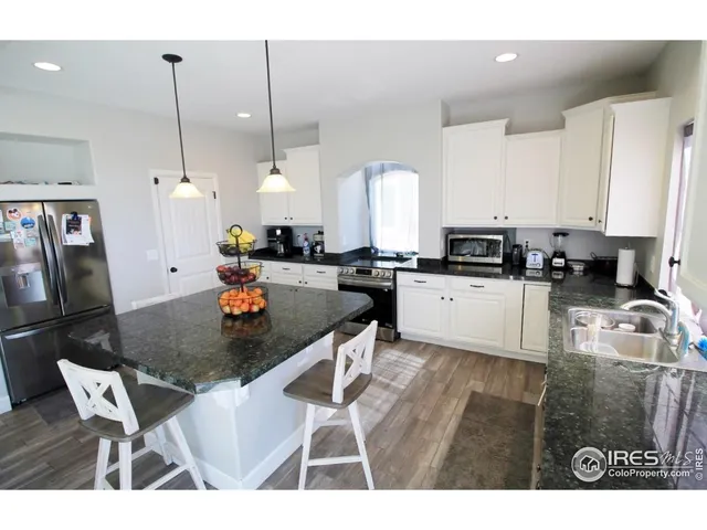 a kitchen with stainless steel appliances granite countertop a table chairs sink refrigerator and cabinets