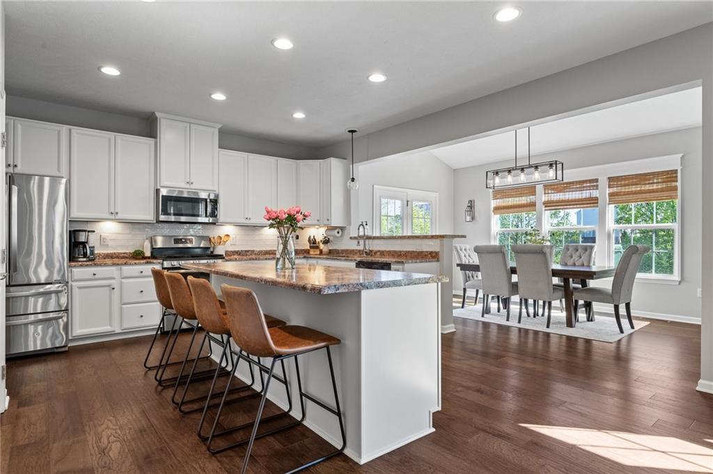 110 Brook Side Drive Clinton, PA 15026 - Photo 17 of 49 a kitchen with stainless steel appliances granite countertop a stove top oven a refrigerator a dining table and chairs with wooden floor