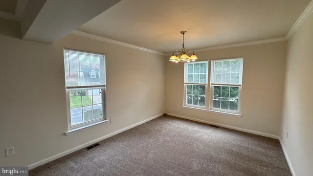 an empty room with chandelier fan and windows