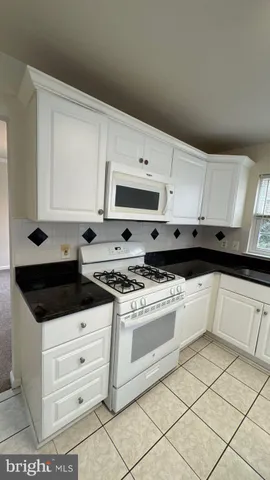 a kitchen with white cabinets and appliances