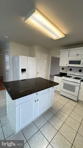 a kitchen with granite countertop a sink and white cabinets